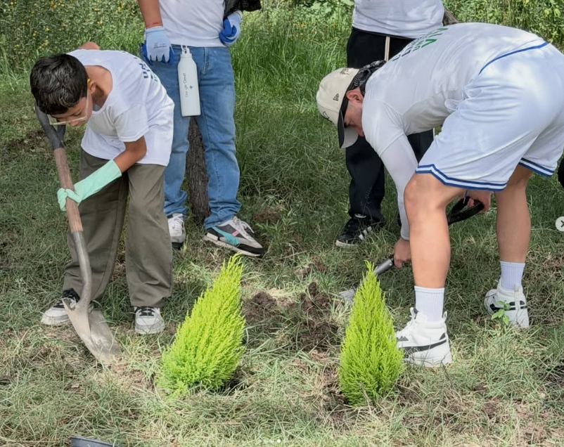 Voluntarios y niños reforestando con palas en las áreas verdes del lago